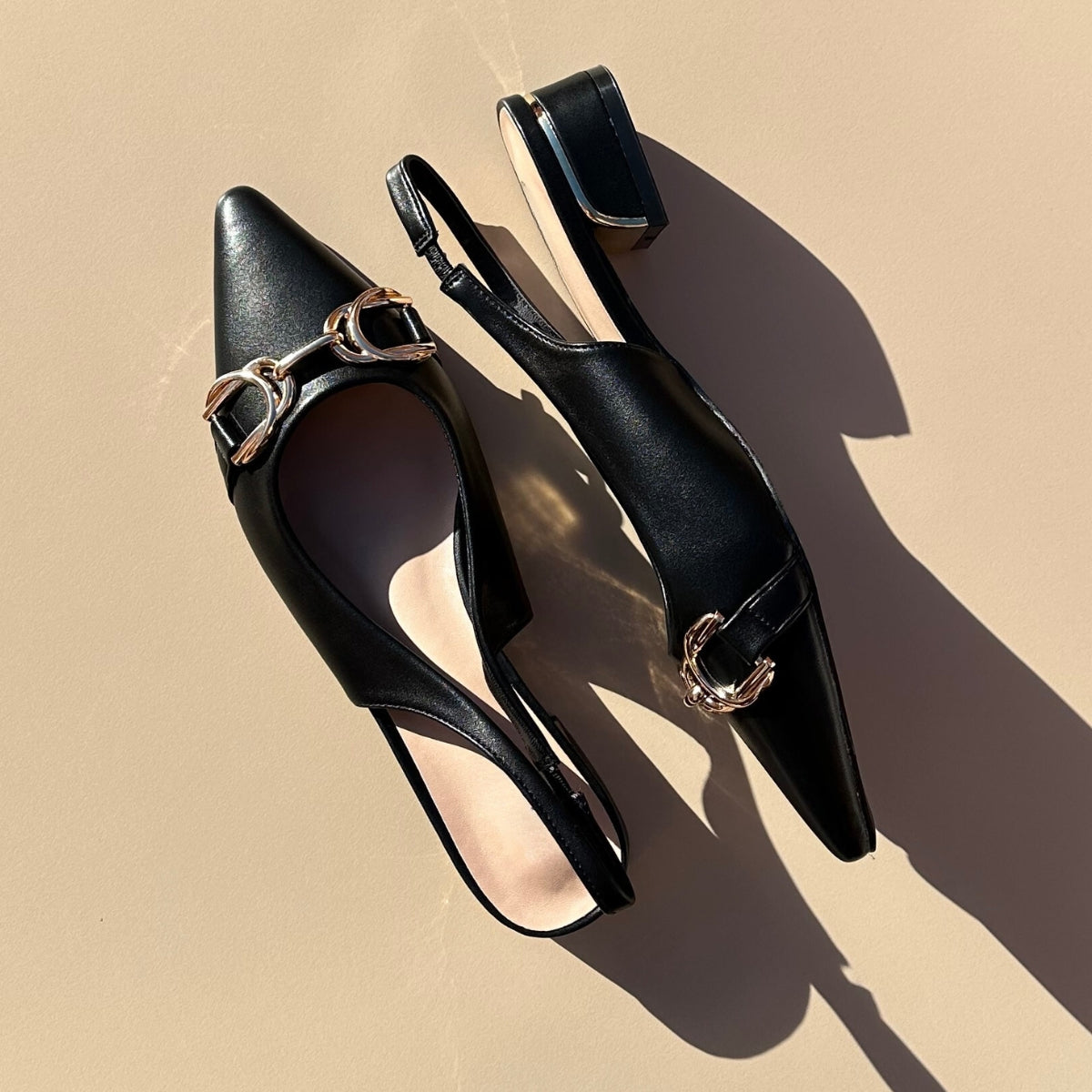 Ballerines slingback en cuir synthétiques noir dotées d'un bout pointu avec motif gold. Confortables et élégantes, elles ajoutent une touche de sophistication à toutes vos tenues. Parfaites pour une journée de travail ou une soirée spéciale, ces ballerines sauront vous faire sentir à la fois confortable et chic. Faites-vous plaisir avec ces chaussures classiques et intemporelles.