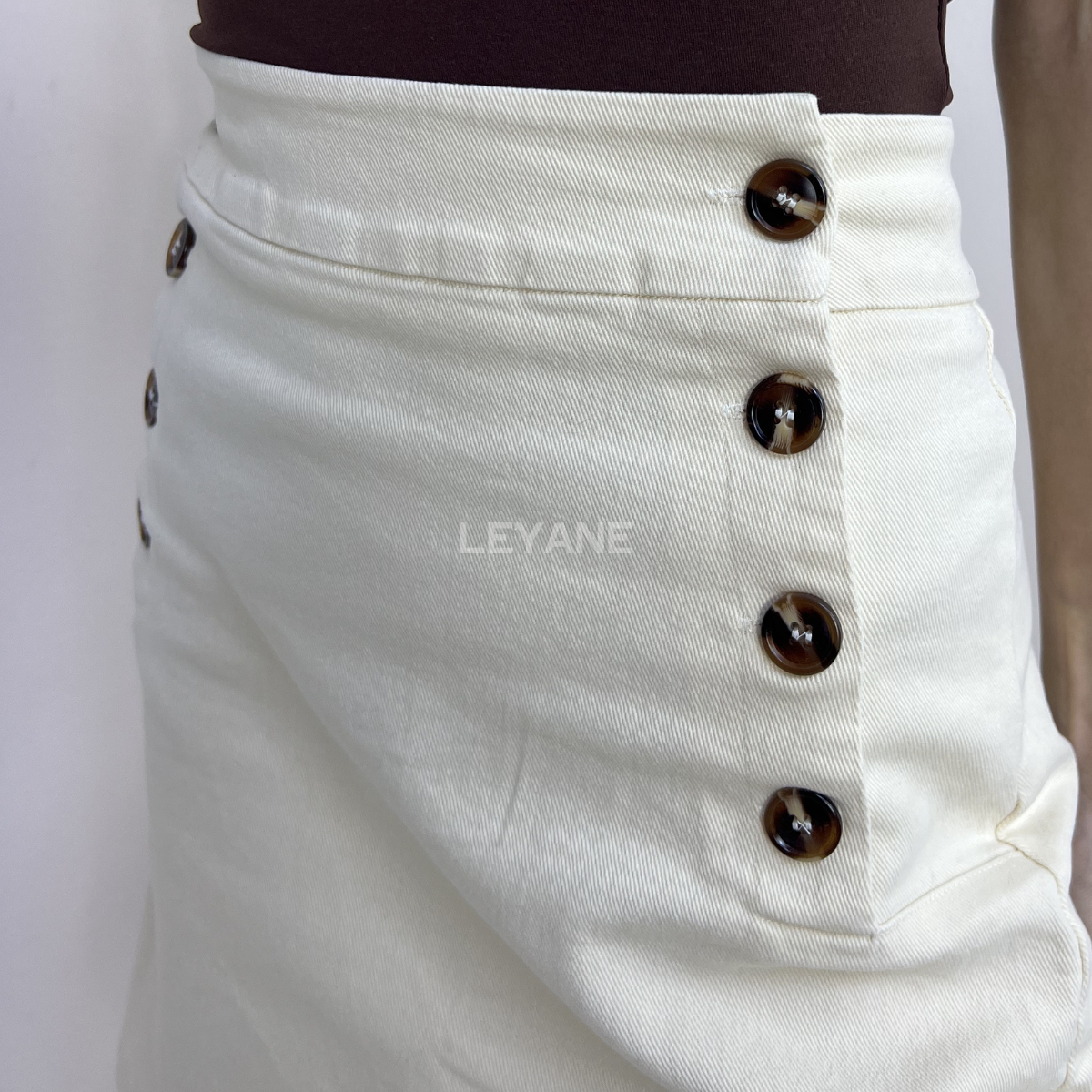 jupe femme, jupe courte beige, jupe taille haute femme, jupe chic femme, jupe boutons décoratifs, jupe élégante femme, jupe casual chic, jupe tendance femme, jupe beige été, jupe mode femme, jupe minimaliste femme, jupe style élégant, jupe moderne femme.